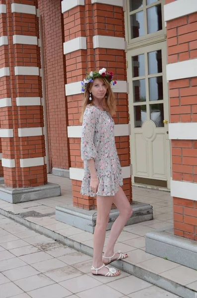 Uma menina com cabelos longos em uma coroa de flores e um vestido de verão — Fotografia de Stock