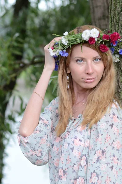 Uma menina com cabelos longos em uma coroa de flores e um vestido de verão — Fotografia de Stock