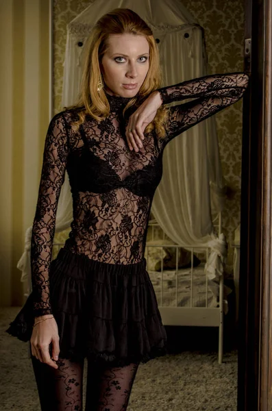 Beautiful blond woman in elegant lace dress at the door to the bedroom — Stock Photo, Image