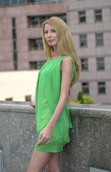 Красивая блондинка в зеленом коротком летнем платье на улицах города — стоковое фото