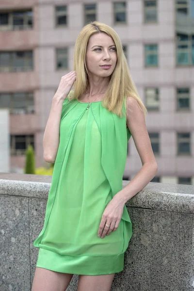 Красивая блондинка в зеленом коротком летнем платье на улицах города — стоковое фото