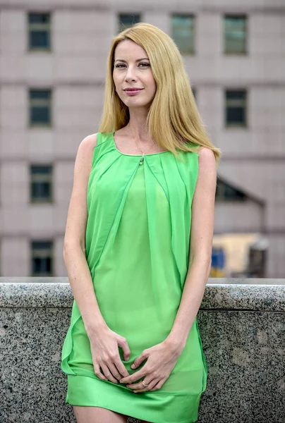 市内の路上で緑の短い夏で美しいブロンドの女の子のドレスします。 — ストック写真