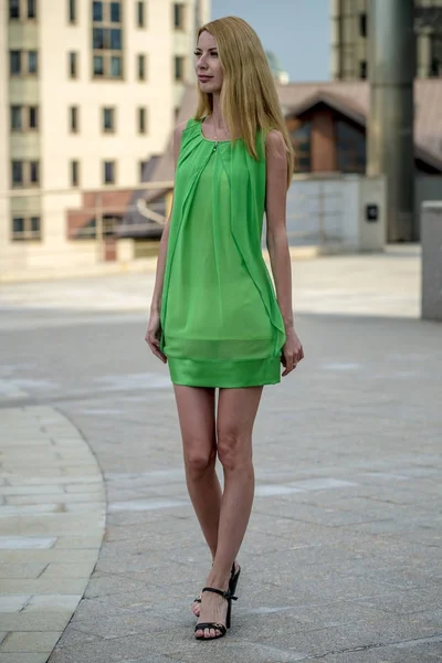 Menina loira bonita em um vestido de verão curto verde nas ruas da cidade — Fotografia de Stock