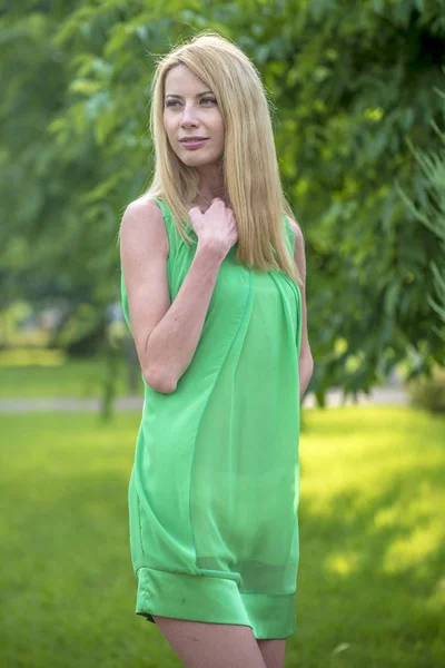 Красива блондинка в зеленій короткій літній сукні на вулицях міста — стокове фото