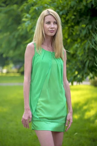 Szép szőke lány egy zöld rövid nyári ruha, a város utcáin — Stock Fotó
