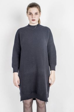 Bir gri uzun sıcak süveterin içinde oturan genç güzel kız