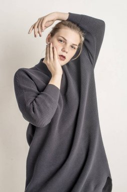 Bir gri uzun sıcak süveterin içinde oturan genç güzel kız