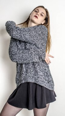 Bir gri uzun sıcak süveterin içinde oturan genç güzel kız