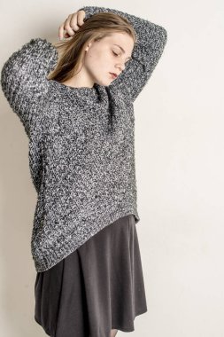 Bir gri uzun sıcak süveterin içinde oturan genç güzel kız