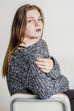 Bir gri uzun sıcak süveterin içinde oturan genç güzel kız