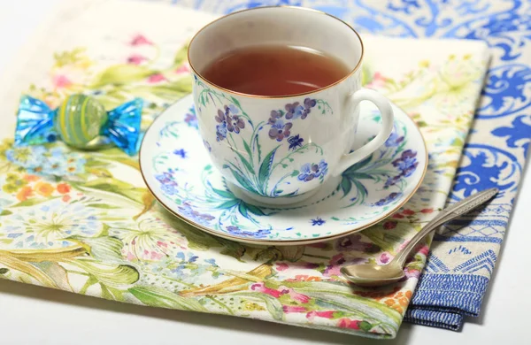 Thé dans une belle tasse avec un motif de fleurs sur une serviette — Photo