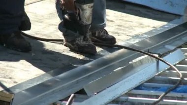 Çatıya metal çıkıntı döşeyen çatıcılar çivi tabancasıyla güvene alıyorlar.