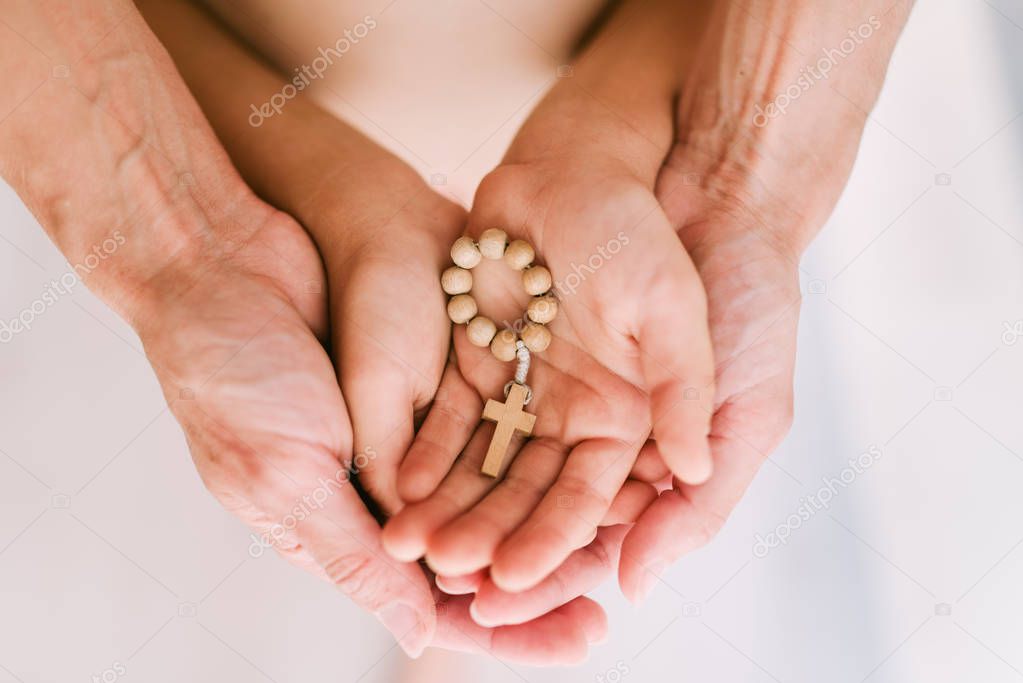 Christian rosary in the hands of mother and child