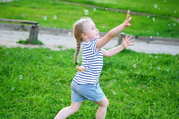 Αξιολάτρευτο κοριτσάκι παίζει στο πάρκο καλοκαίρι με σαπουνόφουσκες — Φωτογραφία Αρχείου