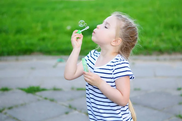 Küçük bir kız yaz parkta sabun köpüğü üfleme — Stok fotoğraf