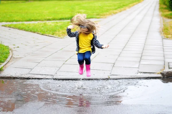 夏の雨の後水たまりにジャンプ幸せなかわいい女の子 — ストック写真