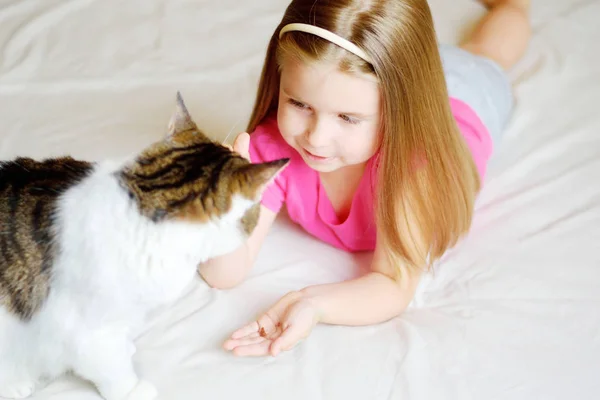 Schattig klein meisje haar kat voeden — Stockfoto