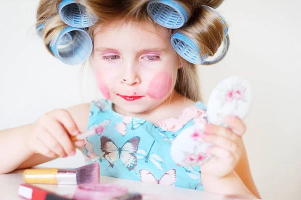 Очаровательная забавная маленькая девочка делает макияж с маминой косметикой — стоковое фото