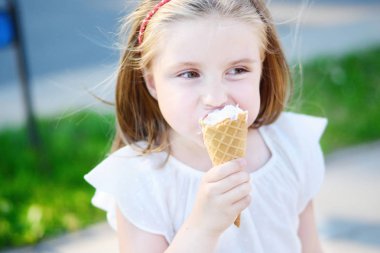 Sevimli küçük kız yaz gün sıcak güneşli park, lezzetli dondurma yemek