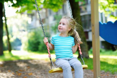 Sevimli kız yaz günü salıncakta eğleniyor.