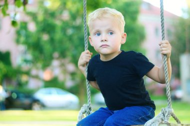 Sevimli küçük sarışın çocuk parkında eğleniyor.