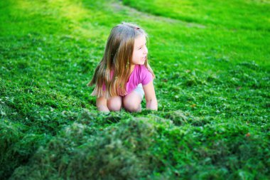 Sevimli kız kesilerek çim ile oynamak