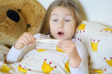 Hasta kız yatakta yatan bir termometre ile