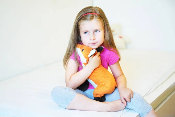 Rozkošná holčička objímání liška Plyšová hračka v posteli — Stock fotografie