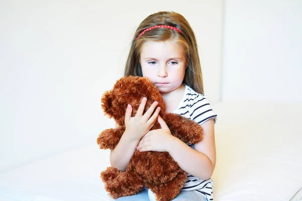 Deprimida niña abrazando oso de peluche — Foto de Stock