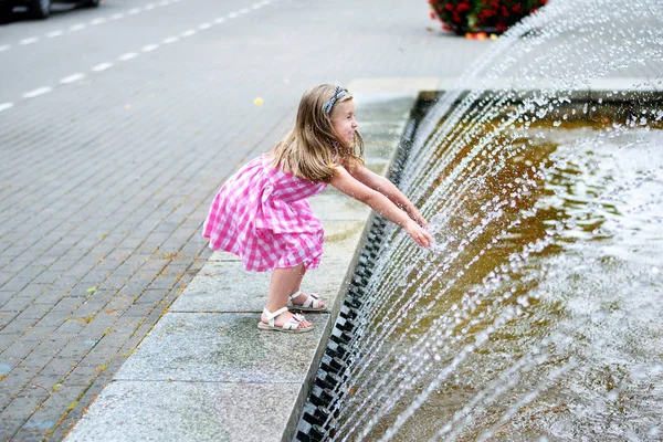 Bir şehir çeşme ile sıcak ve güneşli yaz gününde oynayan sevimli küçük kız — Stok fotoğraf