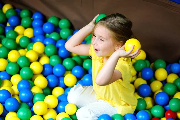 Szczęśliwa dziewczynka gra kolorowe kulki plastikowe placu zabaw — Zdjęcie stockowe
