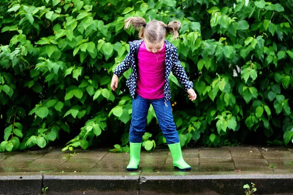 Ευτυχισμένο το χαριτωμένο μικρό κορίτσι άλματα σε λακκούβα μετά τη βροχή το καλοκαίρι — Φωτογραφία Αρχείου