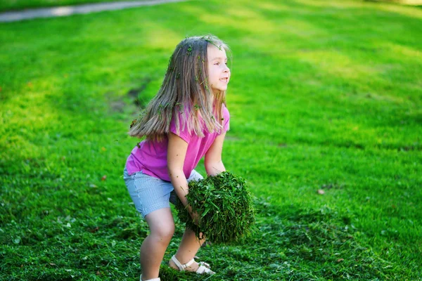 Adorable fille jouer avec l'herbe coupée — Photo