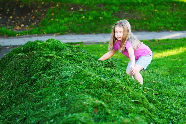 Rozkošné děti hrají s broušená tráva — Stock fotografie