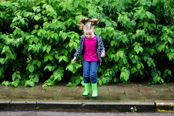 Feliz bonito menina saltando na poça após a chuva no outono — Fotografia de Stock