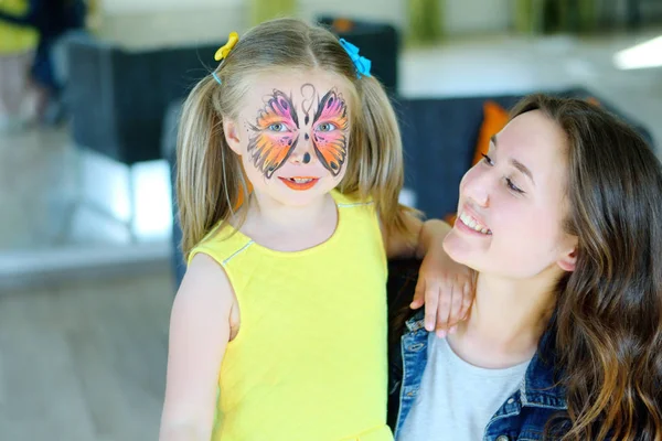 Chica bonita con la pintura de la cara de una mariposa con niñera —  Fotos de Stock