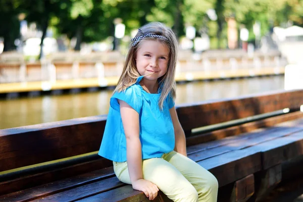 Очаровательная маленькая девочка играет у реки в солнечном парке в прекрасный летний день — стоковое фото