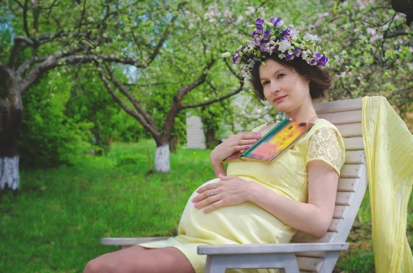 Pretty pregnant woman in a yellow dress and a wreath of flowers — Stock Photo, Image