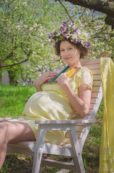 Pretty pregnant woman in a yellow dress and a wreath of flowers — Stock Photo, Image