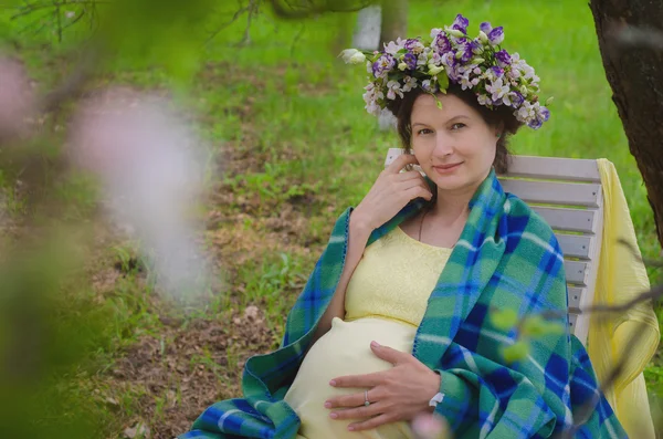 Mulher muito grávida em um vestido amarelo e uma coroa de flores — Fotografia de Stock