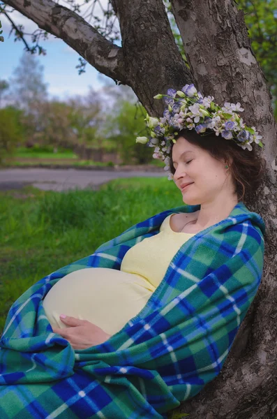 Pretty pregnant woman in a yellow dress and a wreath of flowers — Stock Photo, Image