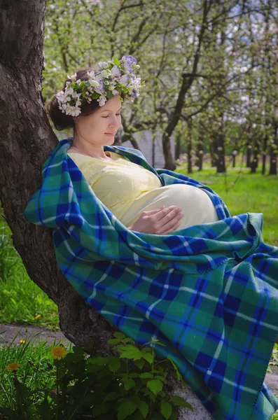 Pretty pregnant woman in a yellow dress and a wreath of flowers — Stock Photo, Image