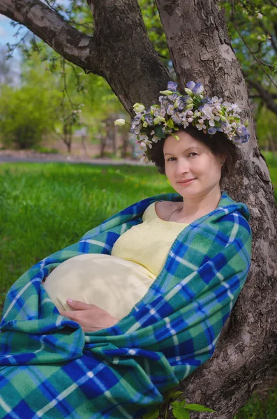 Αρκετά έγκυος γυναίκα σε ένα κίτρινο φόρεμα και ένα στεφάνι από λουλούδια — Φωτογραφία Αρχείου