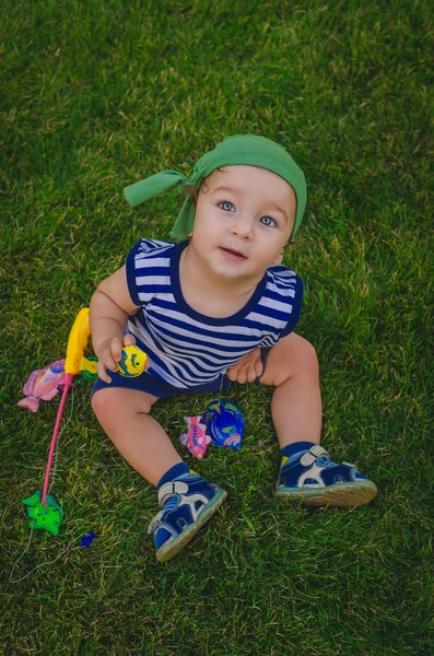 Niño pequeño jugando a los pescadores sentados en una fresca verde la — Foto de Stock