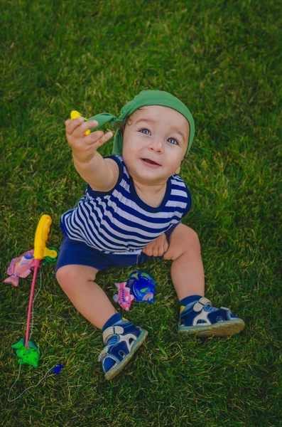 Niño pequeño jugando a los pescadores sentados en una fresca verde la — Foto de Stock