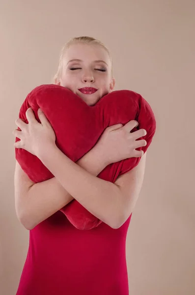 Beautiful young woman in a bright red slinky dress hugging a plu — Stock Photo, Image