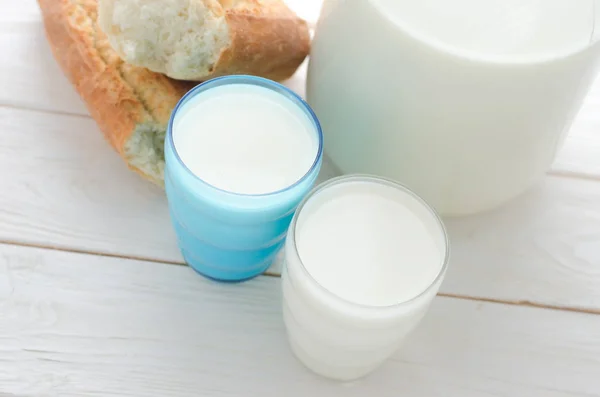Banku i dwie szklanki mleka i bagietki na stole — Zdjęcie stockowe