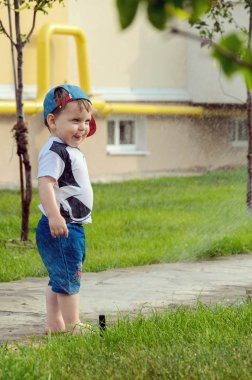 Otomatik sulama çimenler ile oynarken küçük çocuk