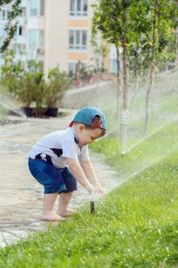 Otomatik sulama çimenler ile oynarken küçük çocuk