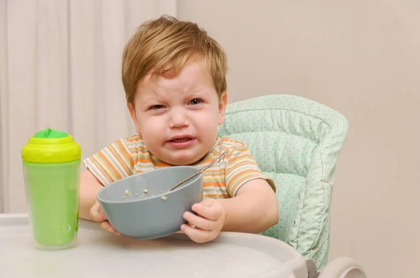 Little blond boy in a striped T-shirt does not want to eat a por — Stock Photo, Image